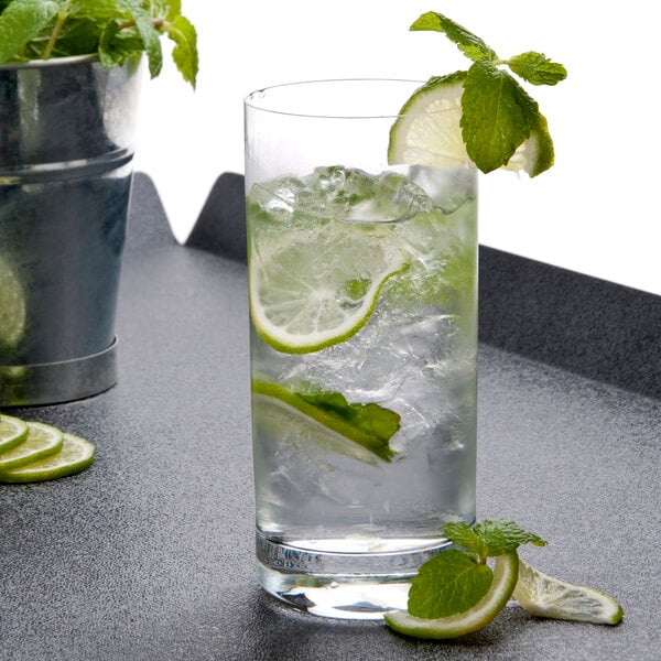 A Stolzle New York tumbler filled with water, ice, and lime slices on a counter.