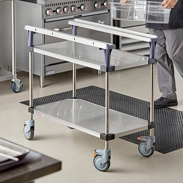 A man using a Metro PrepMate MultiStation with stainless steel shelving in a kitchen.