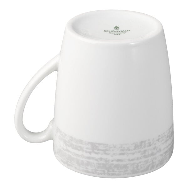 A white porcelain cup with a handle, shown upside down, featuring a subtle gray textured band near the base.