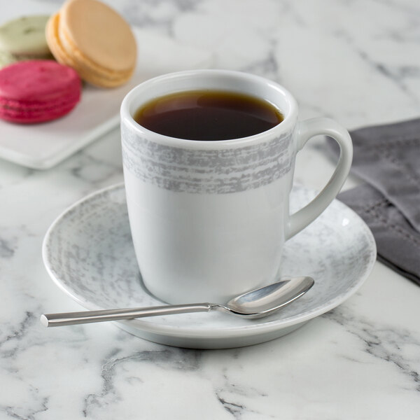 A Schonwald Structure Grey porcelain saucer with a cup of coffee on it with a spoon.