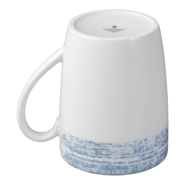 A white porcelain mug with a handle, featuring a blue textured pattern around the bottom, shown upside down.