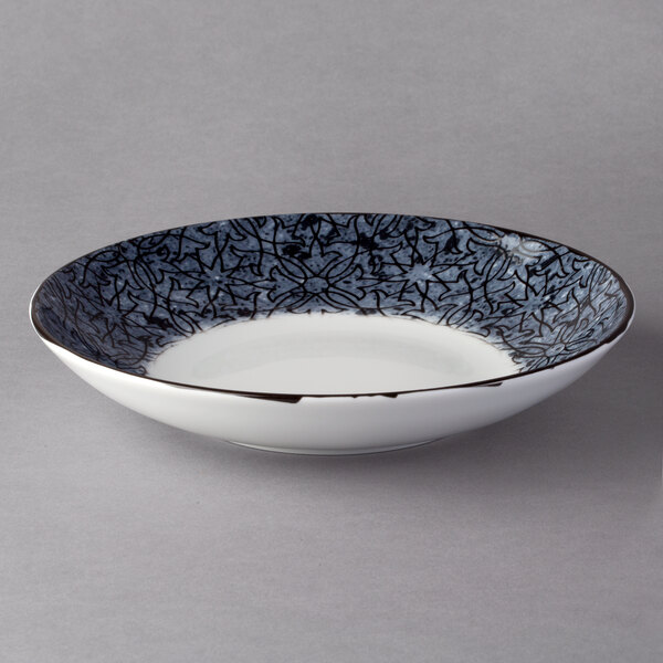 A white porcelain deep coupe plate with black ornaments on it.