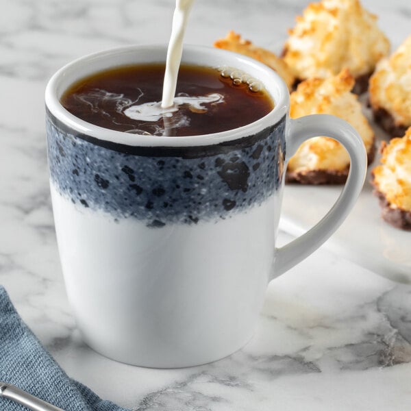 A Schonwald Shabby Chic tall porcelain cup with a handle filled with coffee and milk.