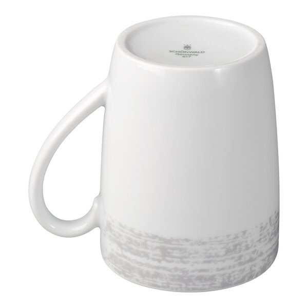 A white porcelain mug with a handle, shown upside down, featuring a subtle gray textured pattern near the base.