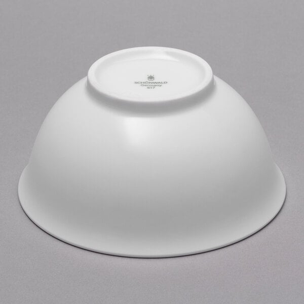 A white Schonwald porcelain bowl with blue ornaments on a gray surface.