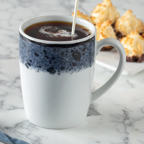 A Schonwald Shabby Chic stone porcelain mug filled with coffee with a spoon in it.