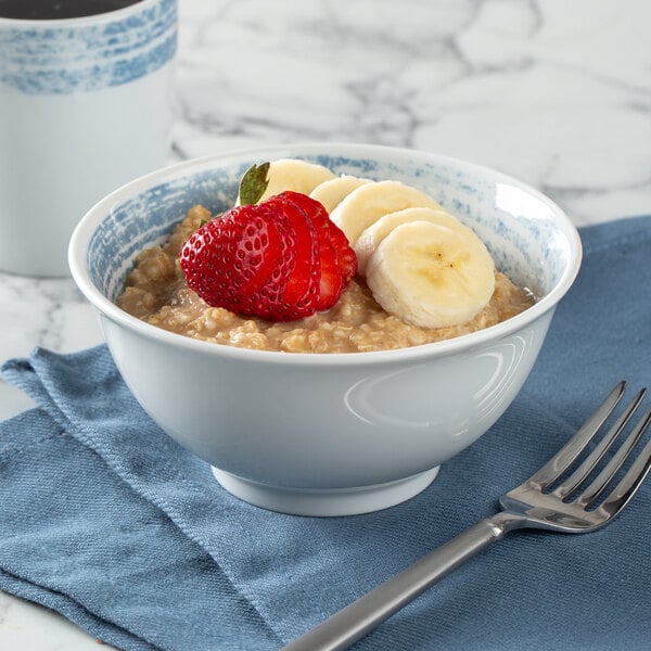 A blue and white Schonwald porcelain bowl filled with oatmeal and fruit with a fork.