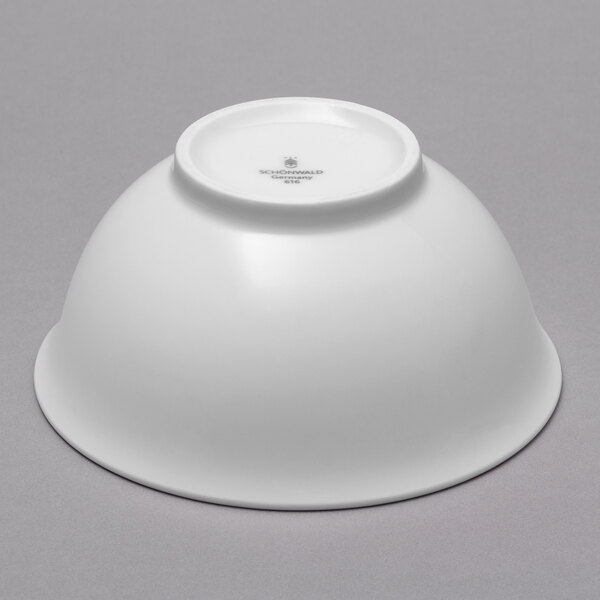 A case of 12 white Schonwald porcelain bowls on a gray surface.