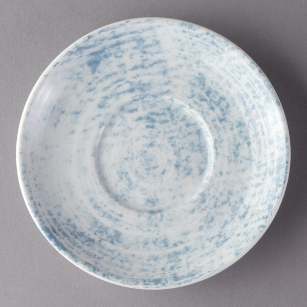 A white porcelain saucer with a blue and white pattern on the bottom.
