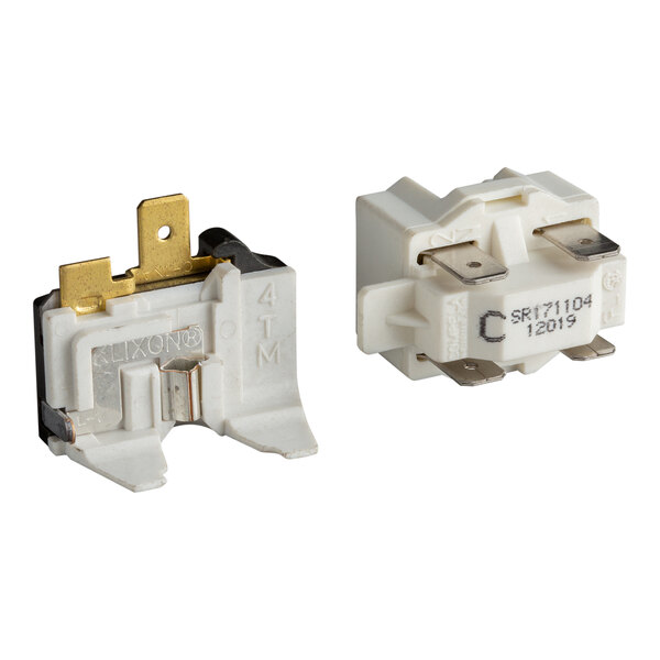 Two white electrical components with metal prongs and terminals, shown from different angles against a white background.