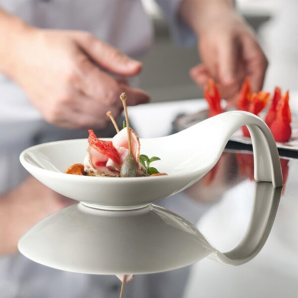 A close-up of food in a Schonwald white porcelain spoon-shaped bowl.