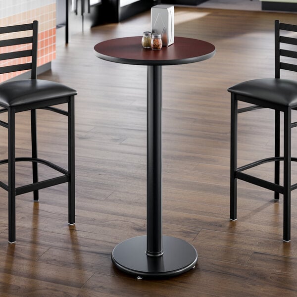 A round, 24-inch laminated table with a reversible cherry and black top, supported by a single black pedestal base.