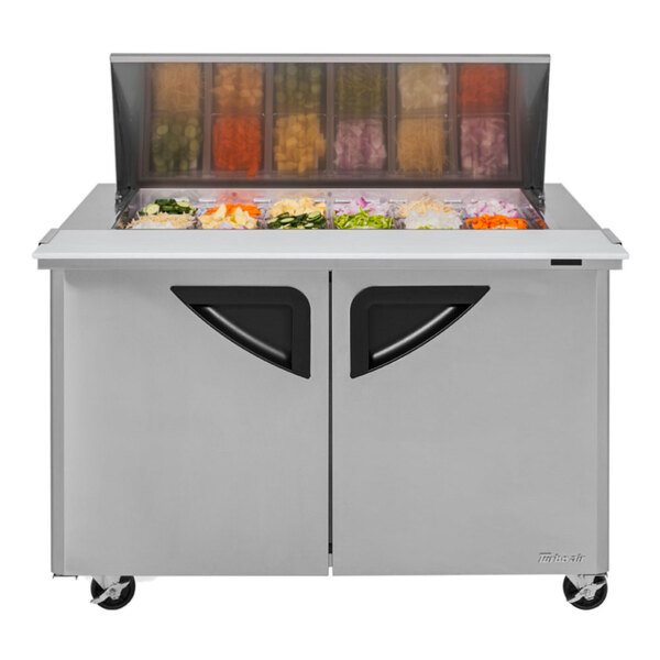 A Turbo Air stainless steel refrigerated sandwich prep table with glass doors filled with food containers.