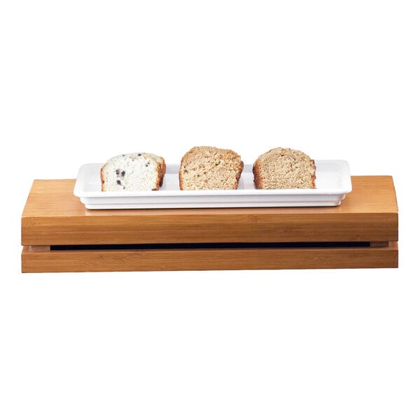 A rectangular bamboo crate riser with a white tray holding three slices of bread on top.