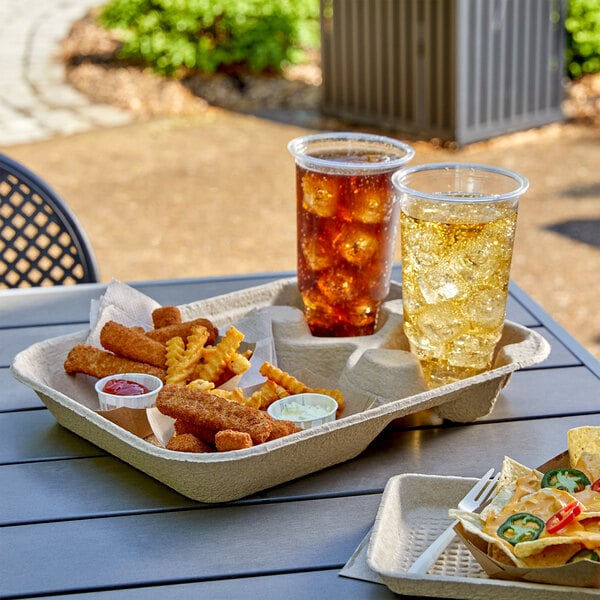 An EcoChoice molded fiber take-out carrier with two drinks and a large tray of food on a table.