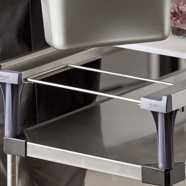 A person using a Metro PrepMate MultiStation Magic Ring on a grey counter to hold metal containers.