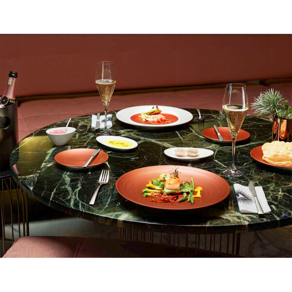 A table with Villeroy & Boch Copper Glow deep bowls filled with food and glasses of champagne.