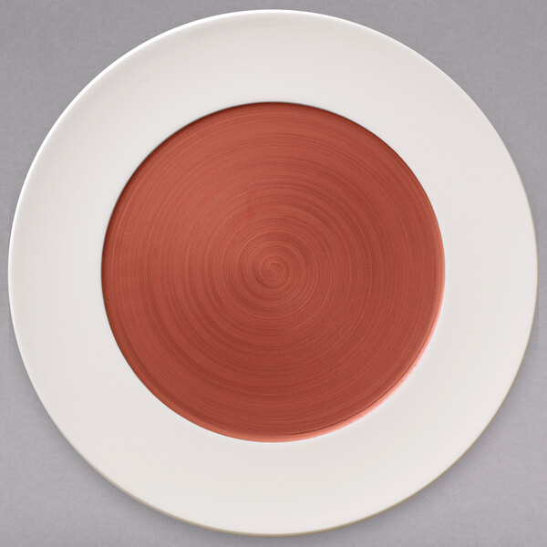 A white porcelain coupe plate with a copper rim and well with a white surface and a red circle on it.