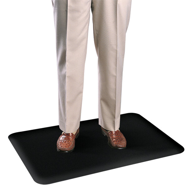 A man standing on a Cactus Mat solid black rubber anti-fatigue mat.