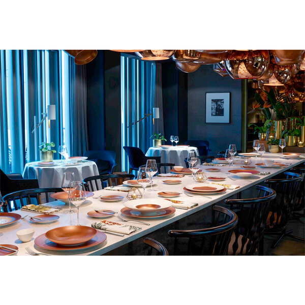 A long table with Villeroy & Boch Copper Glow porcelain deep plates with a copper well and white rim.