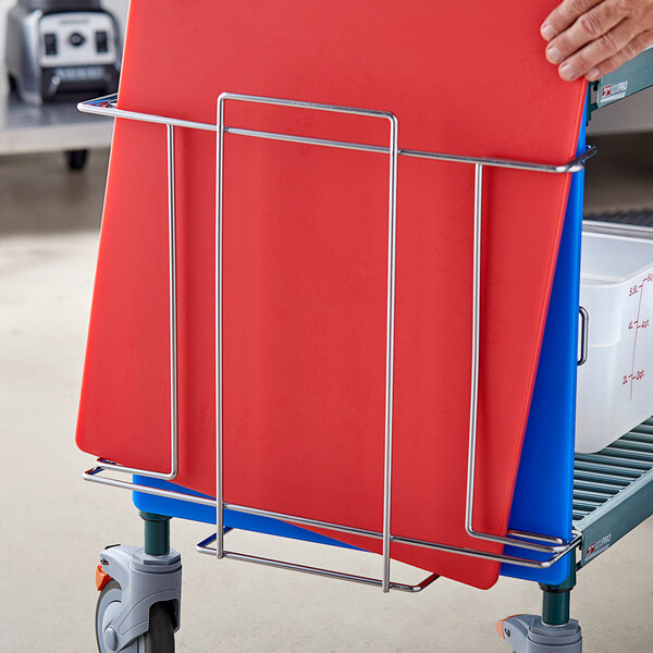 A person holding a cart with a red cutting board in a Metro PrepMate MultiStation.