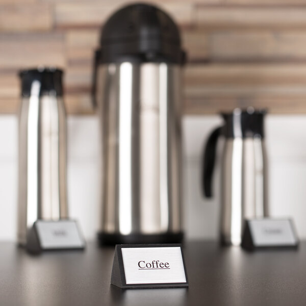 An American Metalcraft black wood table tent sign that says "Coffee" on a table with coffee containers.