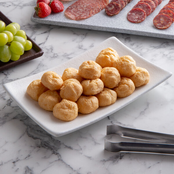 A rectangular white G.E.T. Enterprises Bugambilia fruit bowl filled with cheese and grapes on a table.