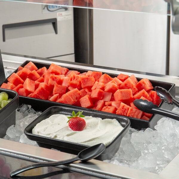 A G.E.T. Enterprises Bugambilia black metal rectangular bowl filled with watermelon on ice.