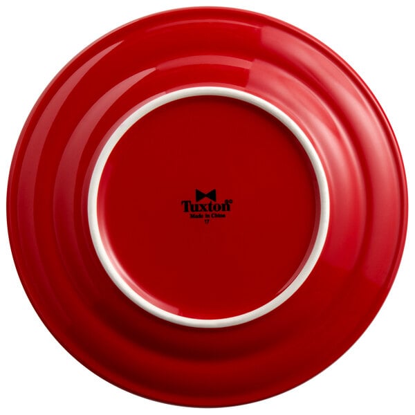 A red Tuxton Concentrix china plate with a white rim.