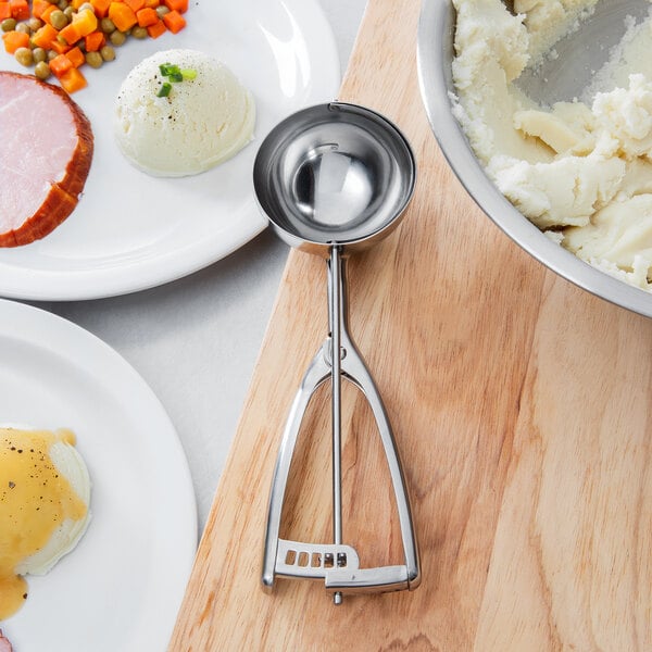 A plate of white cream with a Vollrath stainless steel squeeze handle disher.