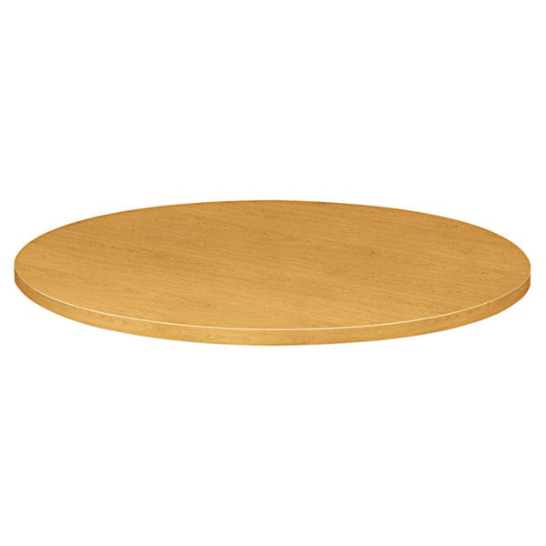 A HON 10500 Series round wooden table top in harvest finish.