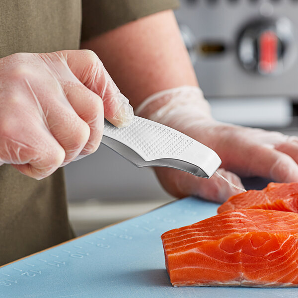 A person using Mercer Culinary fish bone tongs to cut a piece of salmon.