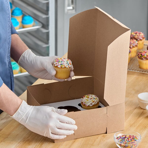 A kraft cupcake or muffin box with a 6-slot reversible insert being filled with cupcakes.
