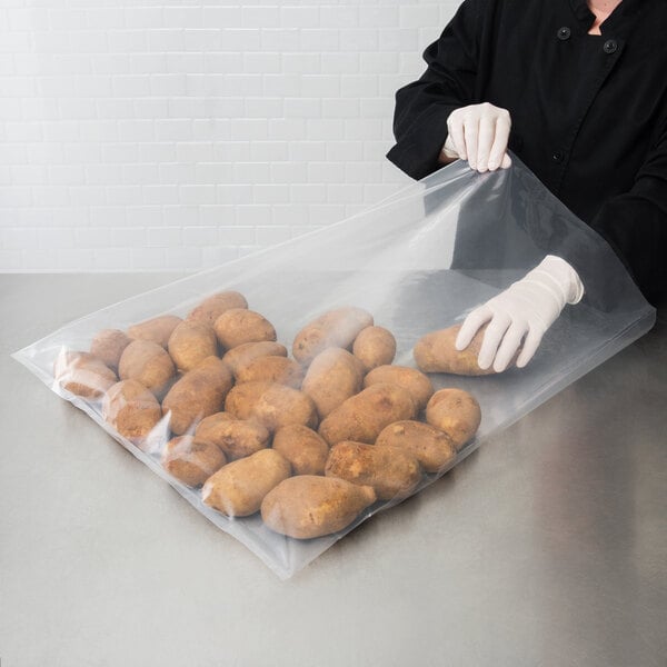 A woman in gloves holding a LK Packaging heavy-duty plastic food bag filled with potatoes.
