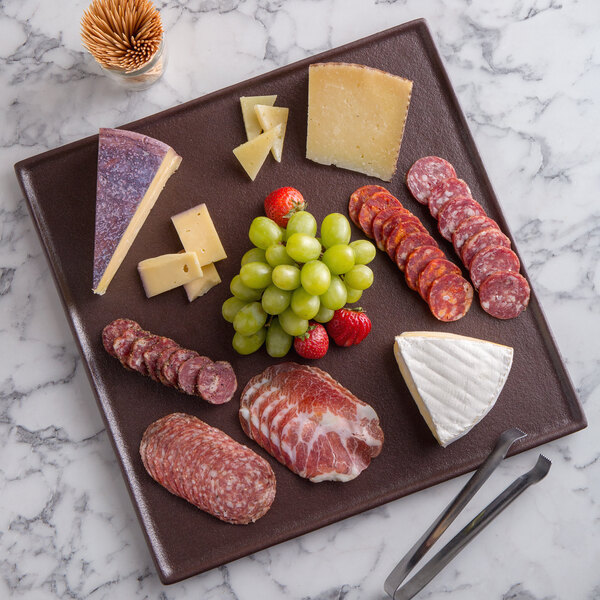 A G.E.T. Enterprises Bugambilia mocha resin-coated aluminum square disc with rim holding cheese and grapes on a marble surface.