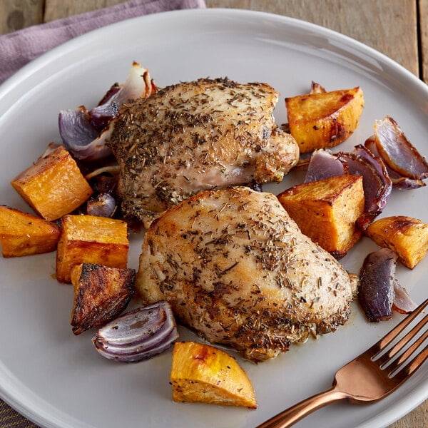 two seasoned chicken thighs on plate with roasted sweet potatoes and onions pieces
