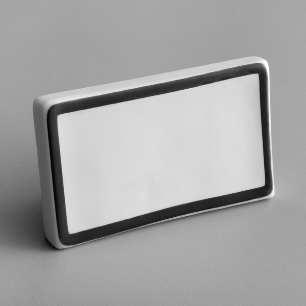 A white rectangular ceramic table tent sign with a black border.
