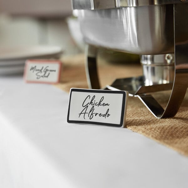 A black ceramic table tent sign with a decal border on a table.