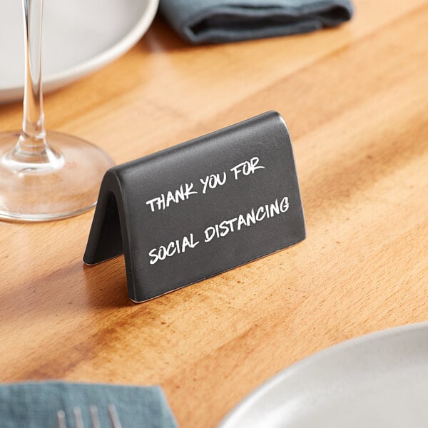 An Acopa matte black ceramic table tent sign with white text on a table.