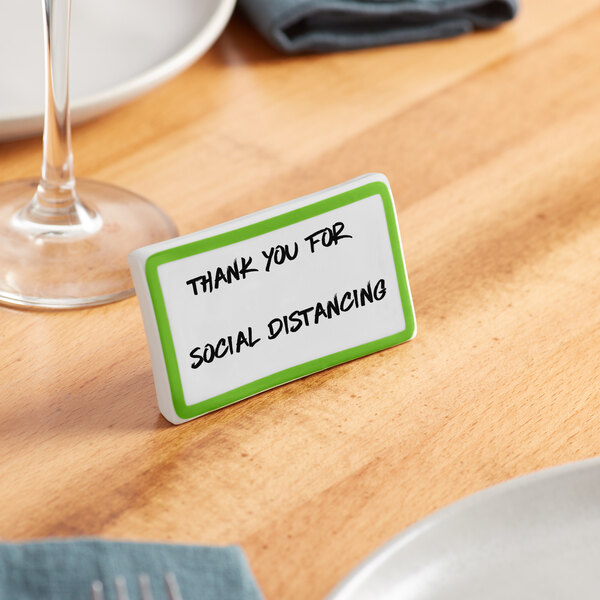 A green ceramic table tent with a border and the words "Thank You for Social Distancing" on it.