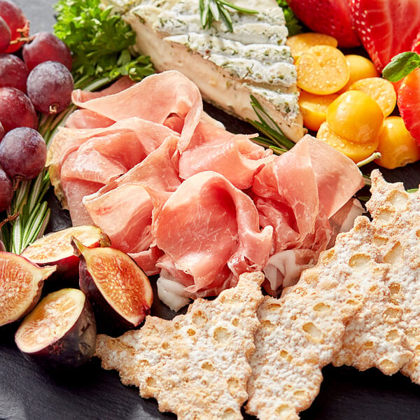 A plate of Citterio boneless prosciutto, cheese, fruit, and crackers.