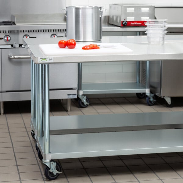 A Regency stainless steel work table on casters in a large kitchen with a large pot on top.