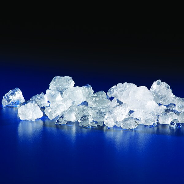 A pile of flake ice from a Manitowoc air cooled ice machine on a blue surface.