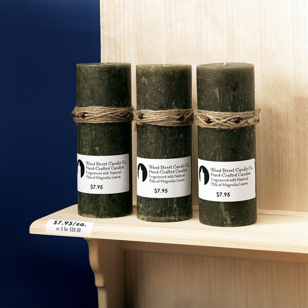 A group of three green candles with a white Avery mailing label tied with twine.