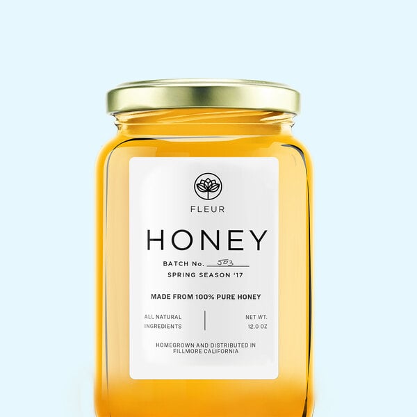 A jar of honey with a white Avery label.
