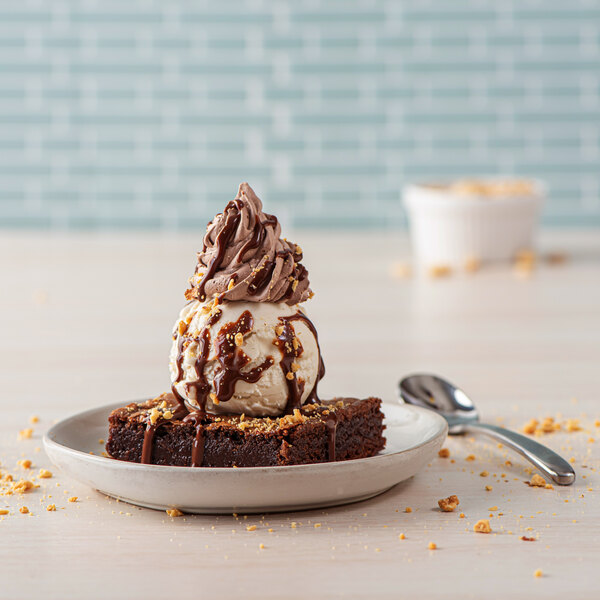 A brownie with Rich's non-dairy whipped chocolate dessert topping and ice cream on top on a plate.