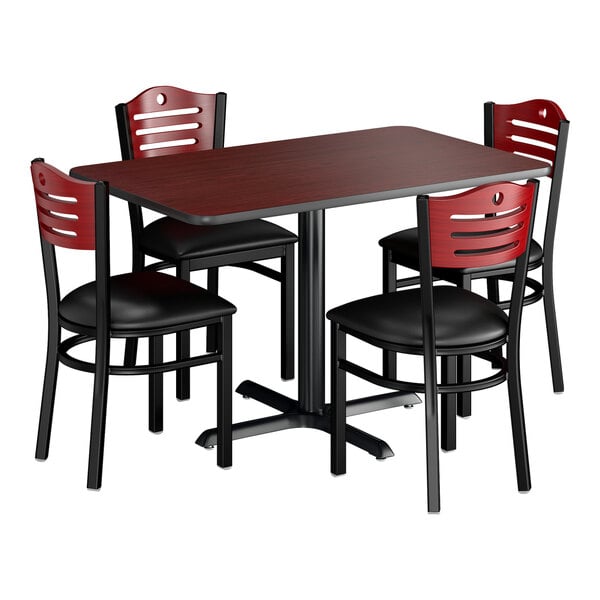 A rectangular dining set with a reversible cherry and black table and four mahogany chairs with padded black seats.