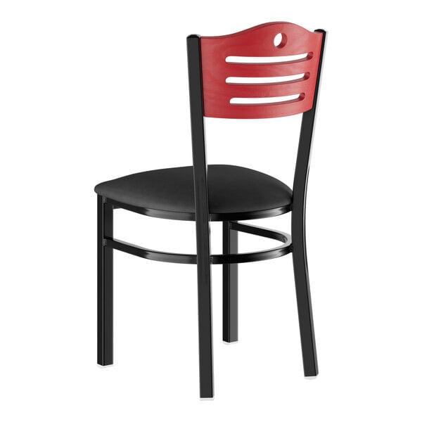 A standard height dining chair with a black padded seat, black metal frame, and a mahogany-colored wooden backrest featuring horizontal cutouts.