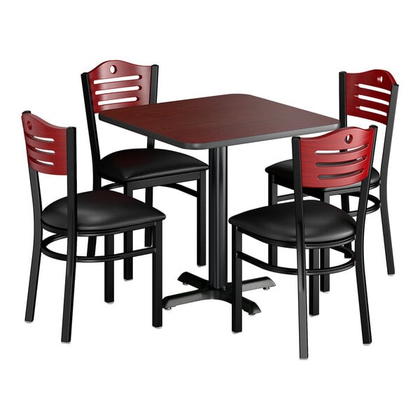 A square dining set with a reversible cherry and black table and four mahogany chairs with black padded seats.