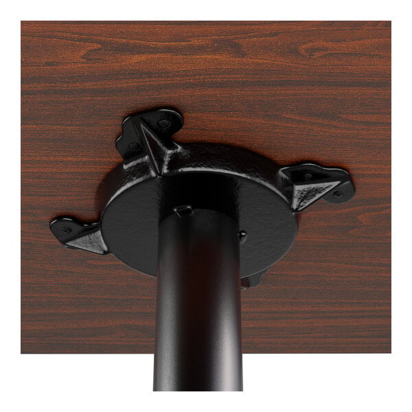 A close-up view of the underside of a wooden dining table showing a black metal mounting bracket attached to a table leg.